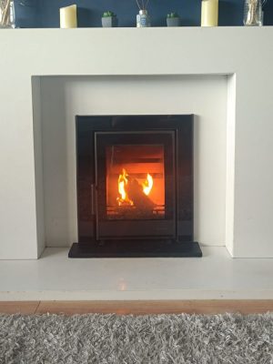 Atlantic Wave 5 insert stove mounted to a white marble lighting fireplace